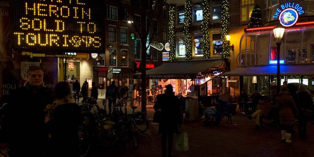 FILE - In this Dec. 5, 2014 file photo an electronic sign outside Amsterdam's famous Bulldog coffee shop, right, warns tourists of "white heroin", an extremely dangerous drug which is being sold as cocaine to tourists in Amsterdam. Police in Amsterdam said Tuesday April 7, 2015, that a 42-year-old man who turned himself in on Saturday could be a dealer who sold white heroin to tourists, telling them that it was cocaine, three tourists have died in recent months and 20 other became unwell after taking heroin. (AP Photo/Peter Dejong, File)