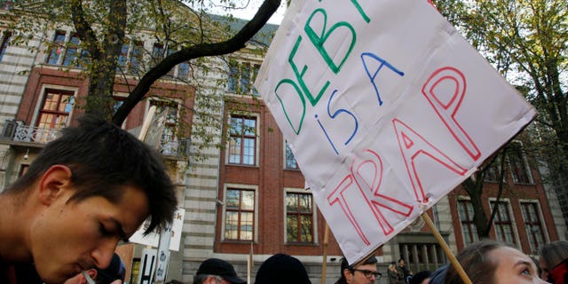 Demonstrators hold placards outside the NYSE Euronext stock exchange, rear, in Amsterdam, Netherlands, Saturday Oct. 15, 2011, during a demonstration in support of the Occupy Wall Street movement.