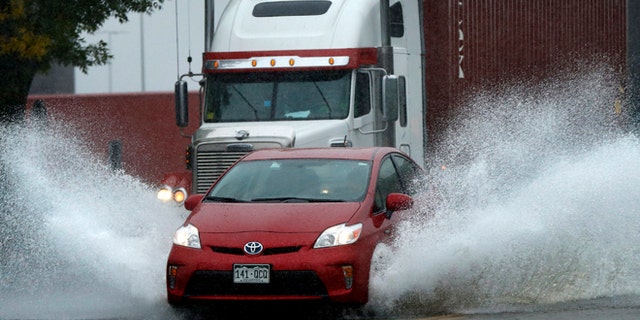 A motorist drives through flooding water in Portland, Maine.