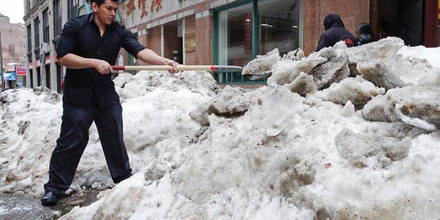 FILE - In this March 4, 2015 file photo, waiter Melvin Angel shovels snow outside the restaurant he works at in the Chinatown neighborhood of Boston. Every work day lost during New England’s historic winter has meant millions of dollars out of the regional economy. Retailers and restaurants were among the hardest hit, but hotels, transportation companies and other tourism businesses struggled too. (AP Photo/Charles Krupa)