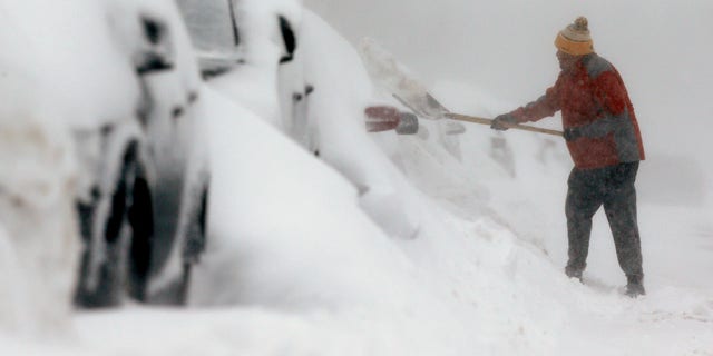 A man shovels snow in the East Boston neighborhood of Boston, Sunday, Feb. 15, 2015. A storm brought a new round of wind-whipped snow to New England on Sunday, threatening white-out conditions in coastal areas and forcing people to contend with a fourth winter onslaught in less than a month. (AP Photo/Michael Dwyer)