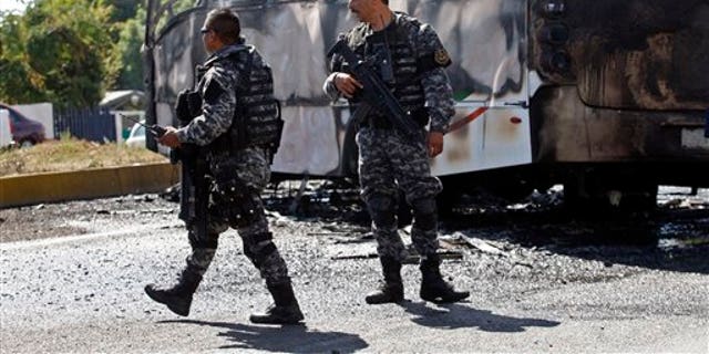 State police stand next to a charred passenger bus, that was extinguished by firefighters in Guadalajara, Mexico, Friday, May 1, 2015.