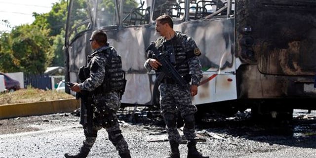 State police stand next to a charred passenger bus, that was extinguished by firefighters in Guadalajara, Mexico, Friday, May 1, 2015.