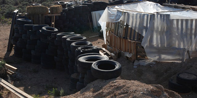 Tires form a wall at a squalid makeshift living compound in Amalia, New Mexico, on Friday, where five adults were arrested on child abuse charges and remains of a boy were found.