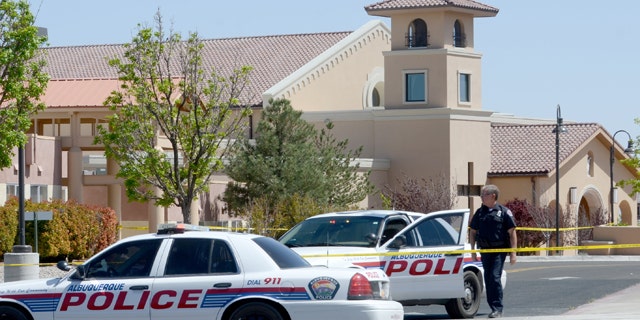 April 28, 2013: An Albuquerque Police officer walks behind the tape at St. Jude Thaddeus Catholic Church.