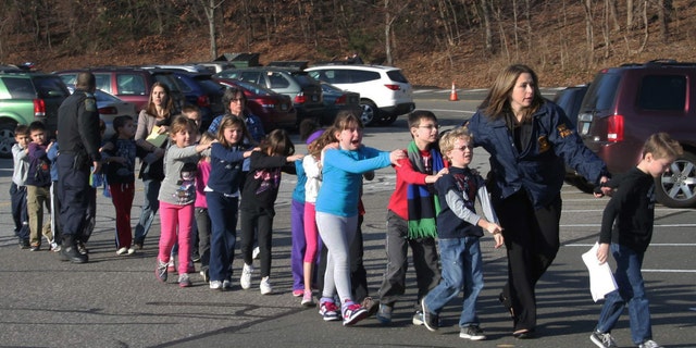 In this photo provided by the Newtown Bee, Connecticut State Police lead a line of children from the Sandy Hook Elementary School in Newtown, Conn. on Friday, Dec. 14, 2012 after a shooting at the school. (AP Photo/Newtown Bee, Shannon Hicks, File)