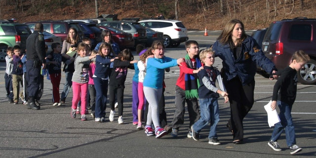 In this photo provided by the Newtown Bee, Connecticut State Police lead a line of children from the Sandy Hook Elementary School in Newtown, Conn. on Friday, Dec. 14, 2012 after a shooting at the school. (AP Photo/Newtown Bee, Shannon Hicks, File)