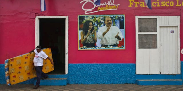 A man leaves the Sandinista National Front Party headquarters, in Masaya, Nicaragua, Saturday, Nov. 5, 2016. Nicaraguan President Daniel Ortega, pictured on the facade of the headquarters with his running mate and wife, Rosario Murillo, appears to have a clear path to a third consecutive term following recent moves that weakened the countryââ¬â¢s opposition. (AP Photo/Esteban Felix)