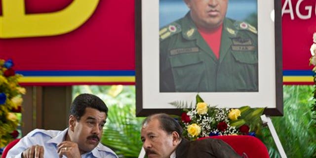 Under a portrait of the late Hugo Chavez, Venezuela's President Nicolas Maduro, left, talks with Nicaragua's President Daniel Ortega during the 8th Petrocaribe Summit in Managua, Nicaragua. (AP Photo/Esteban Felix, File)