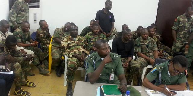 In this photo taken with a mobile phone Tuesday, Sept. 16. 2014 in Abuja Nigeria. Unidentified military prosecutors sit in the front row, while soldiers accused of an attack on their commander appear before a court martial in Abuja. Twelve soldiers fighting an Islamic insurgency in northeast Nigeria have been sentenced to death by firing squad for mutiny and attempted murder of their commanding officer. In a decision read early Tuesday by Brig. Gen. Chukwuemeka Okonkwo, the military tribunal found 12 soldiers guilty and five others innocent. One was sentenced to 28 days in jail with hard labor. ( AP Photo)
