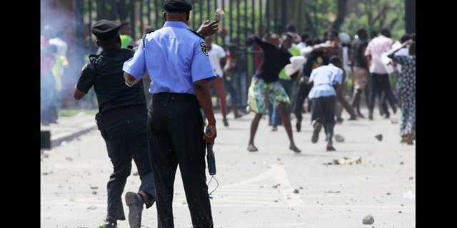 June 1, 2012: A policeman returns a thrown stone as youths run after policemen fired teargas on protesting students of university of Lagos, following the renaming of their school in Lagos, Nigeria.