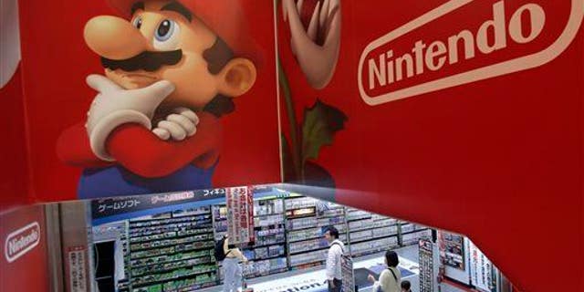 Shoppers walk under the logo of Nintendo and Super Mario characters at an electronics store in Tokyo.