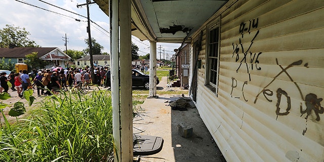 NEW ORLEANS, LA - AUGUST 29:  Revelers march past an abandoned home still marked by rescue markings in the Lower Ninth Ward during a second line parade marking the 10th anniversary of Hurricane Katrina on August 29, 2015 in New Orleans, Louisiana.  A levee breach along the Industrial Canal in the Lower Ninth Ward devastated the area with massive flooding in the aftermath of Hurricane Katrina.  (Photo by Mario Tama/Getty Images)