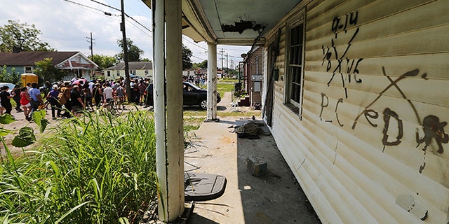 NEW ORLEANS, LA - AUGUST 29: Revelers march past an abandoned home still marked by rescue markings in the Lower Ninth Ward during a second line parade marking the 10th anniversary of Hurricane Katrina on August 29, 2015 in New Orleans, Louisiana. A levee breach along the Industrial Canal in the Lower Ninth Ward devastated the area with massive flooding in the aftermath of Hurricane Katrina. (Photo by Mario Tama/Getty Images)