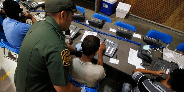FILE: June 18, 2014: A Customs and Border Protection officer helps youths make calls, at the agency's Nogales, Ariz., facility.