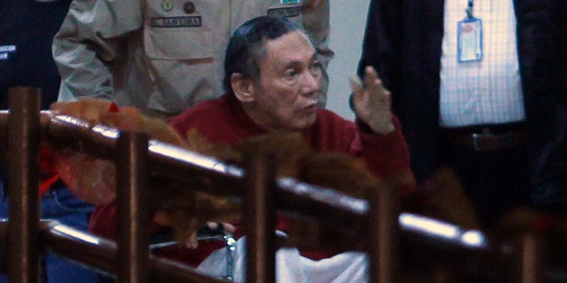 FILE - In this Dec. 11, 2011, file photo, Panama's ex-dictator Manuel Noriega gestures while being carried in a wheelchair by a police officer inside El Renacer prison in the outskirts of Panama City. Speaking to local television network the former Panamanian strongman broke his long silence in a interview from jail, aired on Wednesday, June 24, 2015, asking his compatriots to forgive actions by the military that culminated in the 1989 American invasion. (AP Photo/Esteban Felix, File)