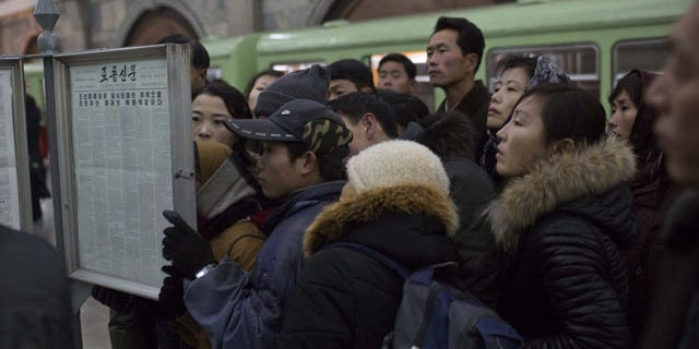 December 13, 2013: North Korean subway commuters gather around a public newspaper stand on the train platform in Pyongyang to read the headlines about Jang Song Thaek, North Korean leader Kim Jong Un's uncle who was executed as a traitor. (AP Photo/David Guttenfelder)