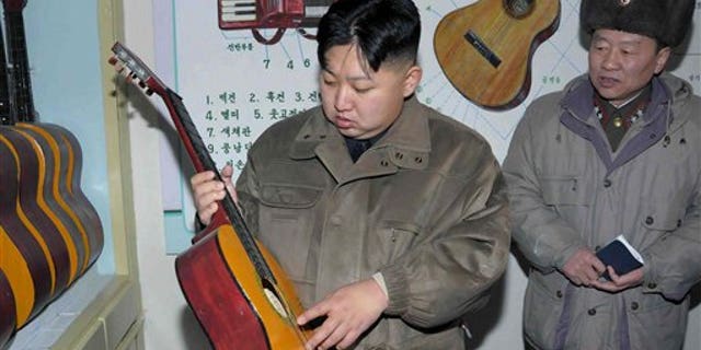 Jan. 19: In this undated photo released by the Korean Central News Agency and distributed in Tokyo by the Korea News Service, North Korean leader Kim Jong Un, center, looks at a guitar at an undisclosed location in North Korea.