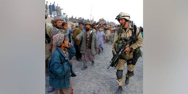 &앰프;nbsp;11 월. 15, 2001: 미국. Air Force special operations soldier walks by an Afghan boy as others loyal to the northern alliance look on, in Khwaja Bahuaddin, 아프가니스탄.