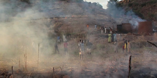 Villagers in the Nuba Mountains region look at the aftermath of a parachute bomb attack from Sudanese forces.