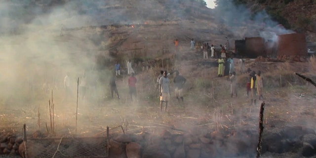 Villagers in the Nuba Mountains region look at the aftermath of a parachute bomb attack from Sudanese forces.