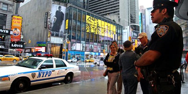 A New York City police officer stands watch in Times Square May 3 as pedestrians pass by. (AP Photo)