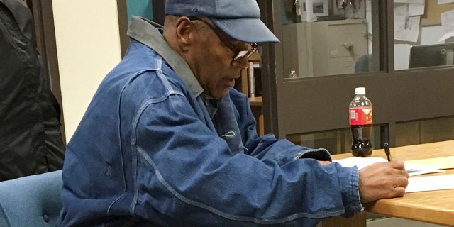 Former football legend O.J. Simpson signs documents at the Lovelock Correctional Center, Saturday, Sept. 30, 2017, in Lovelock, Nev. Simpson was released from the Lovelock Correctional Center in northern Nevada early Sunday, Oct. 1, 2017. (Brooke Keast/Nevada Department of Corrections via AP)
