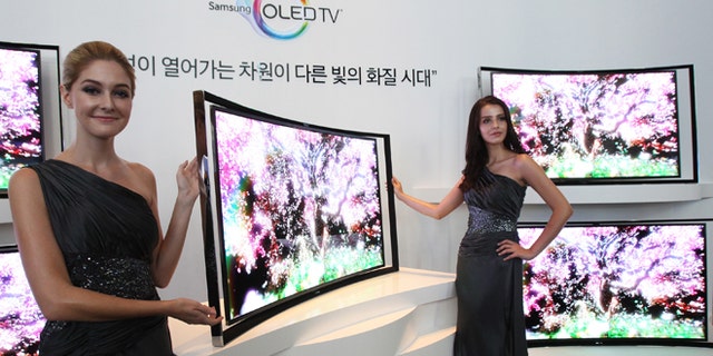 Models pose with a Samsung Electronics Co.'s 55-inch curved OLED TV during a press conference at its headquarters in Seoul, South Korea, Thursday, June 27, 2013. (AP Photo/Ahn Young-joon)