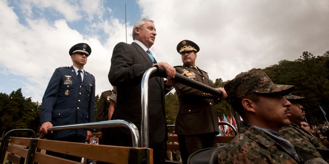 Guatemala's newly sworn-in President Otto Perez Molina, center, and Minister of Defense Ulises Anzueto Giron, right, review the troops during a military ceremony recognizing Perez as commander-in-chief, in Guatemala City, Sunday Jan. 15, 2012. Perez, a retired general, is the first military officer elected as Guatemalan president since the end of a military government 25 years ago. He served in that administration as director of intelligence. (AP Photo/Moises Castillo)