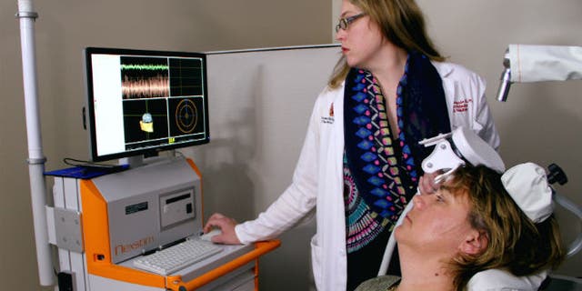 Dr. Marcie Bockbrader adjusts an external brain stimulator on stroke survivor Debbie Hall at The Ohio State University Wexner Medical Center.