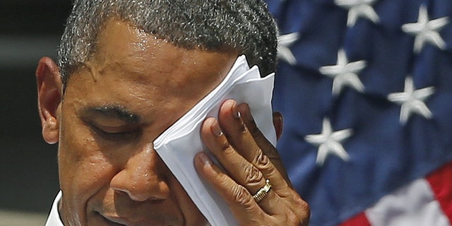 FILE -- June 25, 2013: President Obama wipes his face as he speaks about climate change, Tuesday, June 25, 2013, at Georgetown University in Washington.
