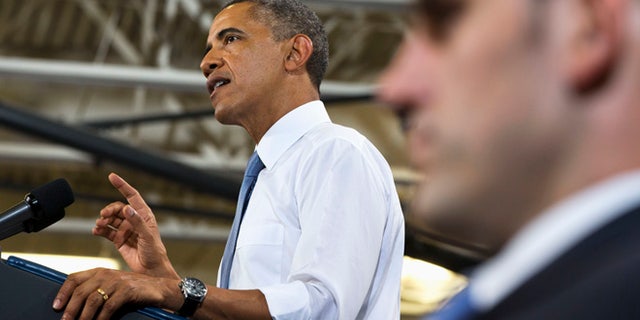 With a Secret Service agent in the foreground, President Obama gestures as he speaks about housing, Tuesday, Aug. 6, 2013, at Desert Vista High School in Phoenix.