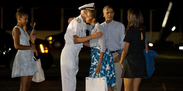 Dec. 20, 2014: First lady Michelle Obama hugs Admiral Samuel Locklear III, Commander, U.S. Pacific Command, with daughter Sasha Obama, left, and Malia Obama, far right, and President Barack Obama as the first family arrives at Pearl Harbor