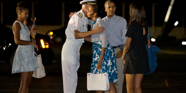 Dec. 20, 2014: First lady Michelle Obama hugs Admiral Samuel Locklear III, Commander, U.S. Pacific Command, with daughter Sasha Obama, left, and Malia Obama, far right, and President Barack Obama as the first family arrives at Pearl Harbor