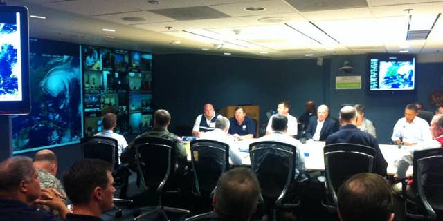 President Obama participates in a conference call on Hurricane Irene. The storm's image can be seen on a screen to the left. (Press pool photo)