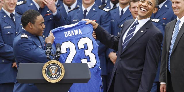 Air Force Academy's defensive back Reggie Rembert presents President Barack Obama with a personalized jersey as head coach Troy Calhoun, right, and running back Jared Tew, top left, look on during a ceremony in the Rose Garden of the White House in Washington, Monday, April 18, 2011, presenting the 2010 Commander-in-Chief Trophy to the Air Force Academy football team. (AP Photo/Charles Dharapak)