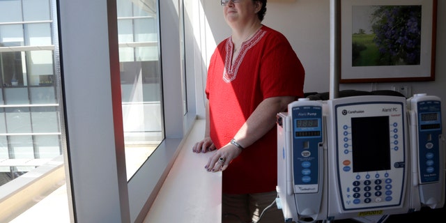 In this Thursday, Sept. 5, 2013 photo, Tracy Smith looks out of a window at the infusion center at Duke Cancer Center in Durham, N.C. Smith was treated at Duke in 2011 for breast cancer that had spread to more than a dozen lymph nodes. Doctors gave her full chemo doses based on her weight. Three times, high fevers put her in the hospital, and one infusion was cut short because doctors thought it was causing wheezing and possible lung damage. But she resumed and finished the intended treatment and has been cancer-free since then. (AP Photo/Gerry Broome)