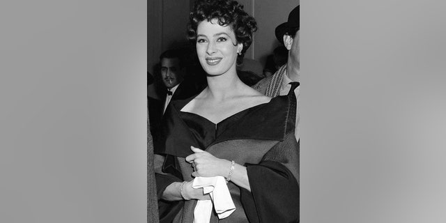 FILE - In this March 4, 1954, file photo, actress Rita Gam stands in lobby of Longacre Theatre at opening of "The Burning Glass" in New York.
