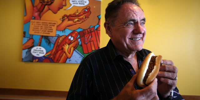 John Galardi, founder of the hot dog chain Wienerschnitzel, poses for a portrait in Lakewood, Calif. He is holding a chili dog.