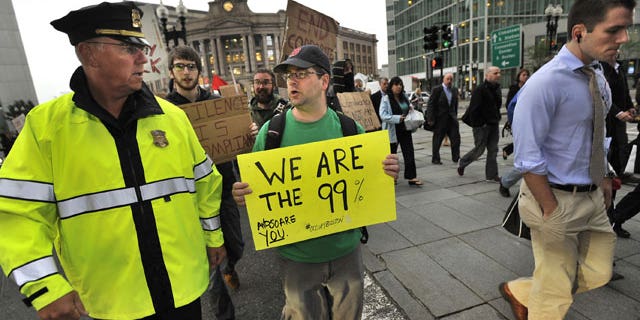 October 3: A marcher speaks with a police officer as they cross a street alongside morning commuters as the marchers set out from the Occupy Boston encampment in Dewey Square in front of the Federal Reserve building, in Boston.