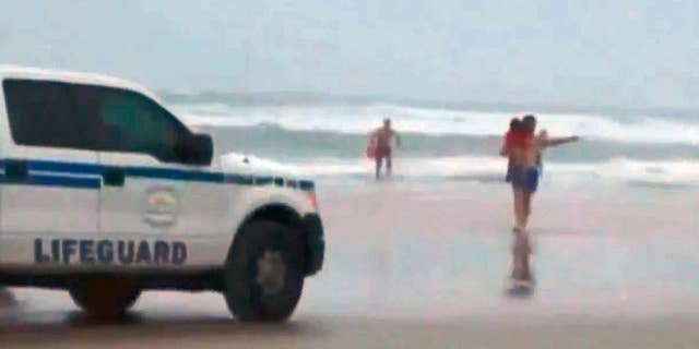 In this image made from video and released by Simon Besner, lifeguards rescue children from a minivan that their mother drove into the Atlantic, Tuesday, March 4, 2014 in Daytona Beach, Fla. Ebony Wilkerson, 31, a pregnant South Carolina woman who drove a minivan carrying her three young children into the ocean surf off Florida had talked about demons before leaving the house, according to her sister who worriedly called police, officials said during a news conference Wednesday. Bystanders and officers helped pull Wilkerson and her children, ages 3, 9 and 10, from their minivan. The children were turned over to welfare authorities. The Volusia County Sheriff's Office says Wilkerson was undergoing a mental evaluation. (AP Photo/Simon Besner)