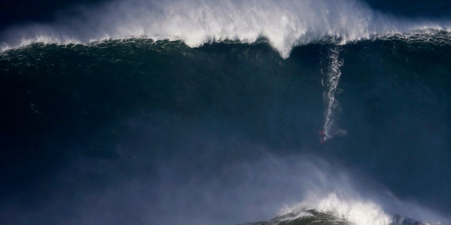 File photo - A surfer drops in on a large wave at Praia do Norte, in Nazare Dec. 11, 2014.