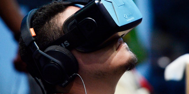 An attendee tries on the Oculus VR Inc. Rift Development Kit 2 headset at the 2014 Electronic Entertainment Expo (E3) in Los Angeles, California June 11, 2014.