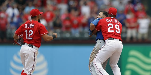 ARLINGTON, TX - MAY 15:  Adrian Beltre #29 of the Texas Rangers holds Jose Bautista #19 of the Toronto Blue Jays after being punched by Rougned Odor #12 in the eighth inning at Globe Life Park in Arlington on May 15, 2016 in Arlington, Texas.  (Photo by Ronald Martinez/Getty Images)