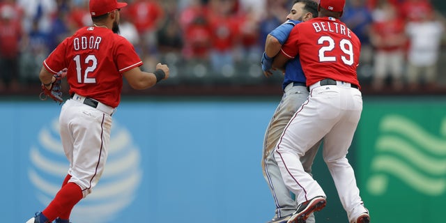 ARLINGTON, TX - MAY 15: Adrian Beltre #29 of the Texas Rangers holds Jose Bautista #19 of the Toronto Blue Jays after being punched by Rougned Odor #12 in the eighth inning at Globe Life Park in Arlington on May 15, 2016 in Arlington, Texas. (Photo by Ronald Martinez/Getty Images)