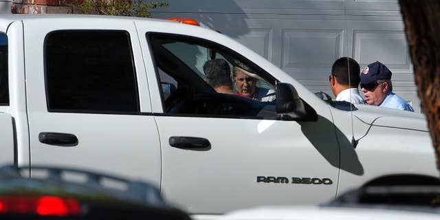 An off-duty Los Angeles police officer, left, talks to investigators next to his vehicle at the scene of an officer involved shooting, Sunday, March 29, 2015, in Santa Clarita, Calif. Authorities have detained a man suspected of shooting at an off-duty Los Angeles police officer from a car before fleeing the scene at a suburban neighborhood in northern Los Angeles county. (AP Photo/Mark J. Terrill)