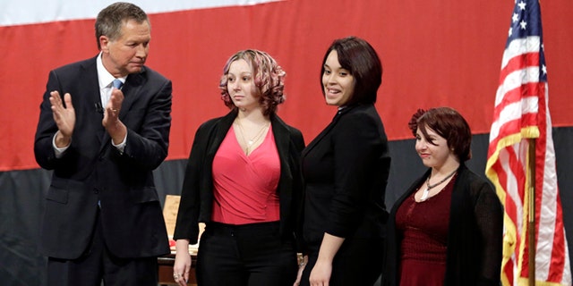 Ohio Gov. John Kasich, from left, introduces Amanda Berry, Gina DeJesus and Michelle Knight during his State of the State address at the Performing Arts Center Monday, Feb. 24, 2014, in Medina, Ohio. The three women, who survived a decades-long captivity in Cleveland before being rescued in May when Berry pushed her way through a door to freedom, received the Governor's Courage Award. (AP Photo/Tony Dejak)