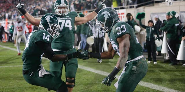 Michigan State running back Jeremy Langford (33) celebrates with wide receiver Tony Lippett (14) and offensive tackle Jack Conklin (74) after his a 33-yard touchdown run against Ohio State during the first half of an NCAA college football game in East Lansing, Mich., Saturday, Nov. 8, 2014. (AP Photo/Carlos Osorio)