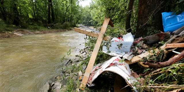 Debris rests on the bank of Red Oak Creek where a mobile home was swept off in Ripley, Ohio, Sunday, July 19, 2015.
