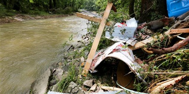 Debris rests on the bank of Red Oak Creek where a mobile home was swept off in Ripley, Ohio, Sunday, July 19, 2015.